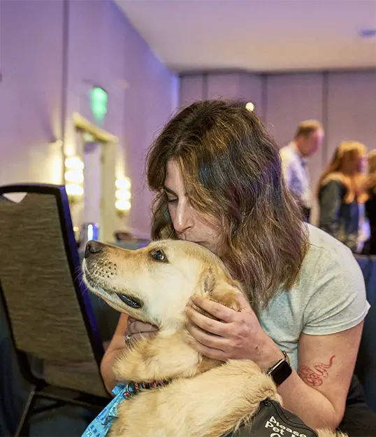 Employee connecting with a therapy dog during a corporate event, highlighting the emotional wellness benefits of therapy dog visits for workplace events